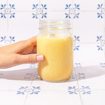 hand holding mason jar of smoothie on tile background