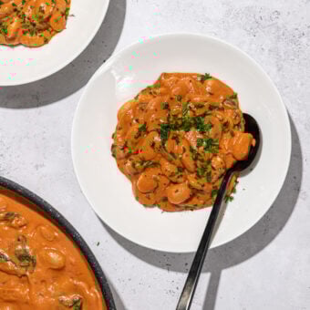 butter beans in creamy rose sauce in white bowls with black spoon