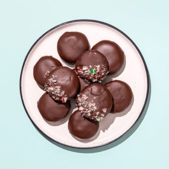 white plate with pile of thin mint cookies on mint background